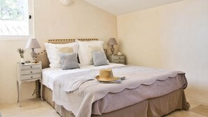 Un dormitorio con una cama, dos mesitas de noche, una ventana y un aplique de pared.