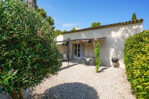 Una casa con patio, una parrilla y una pérgola.