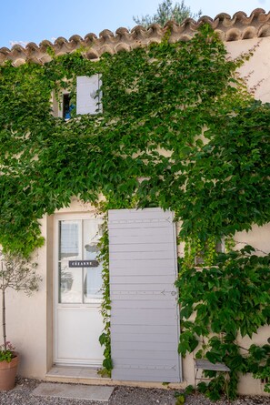 A building with a white door and a window, partially covered by green ivy.