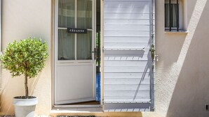Una puerta con un letrero, una planta en maceta y una ventana con persianas.