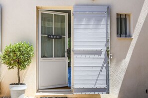 Una puerta con un letrero, una planta en maceta y una ventana con persianas.