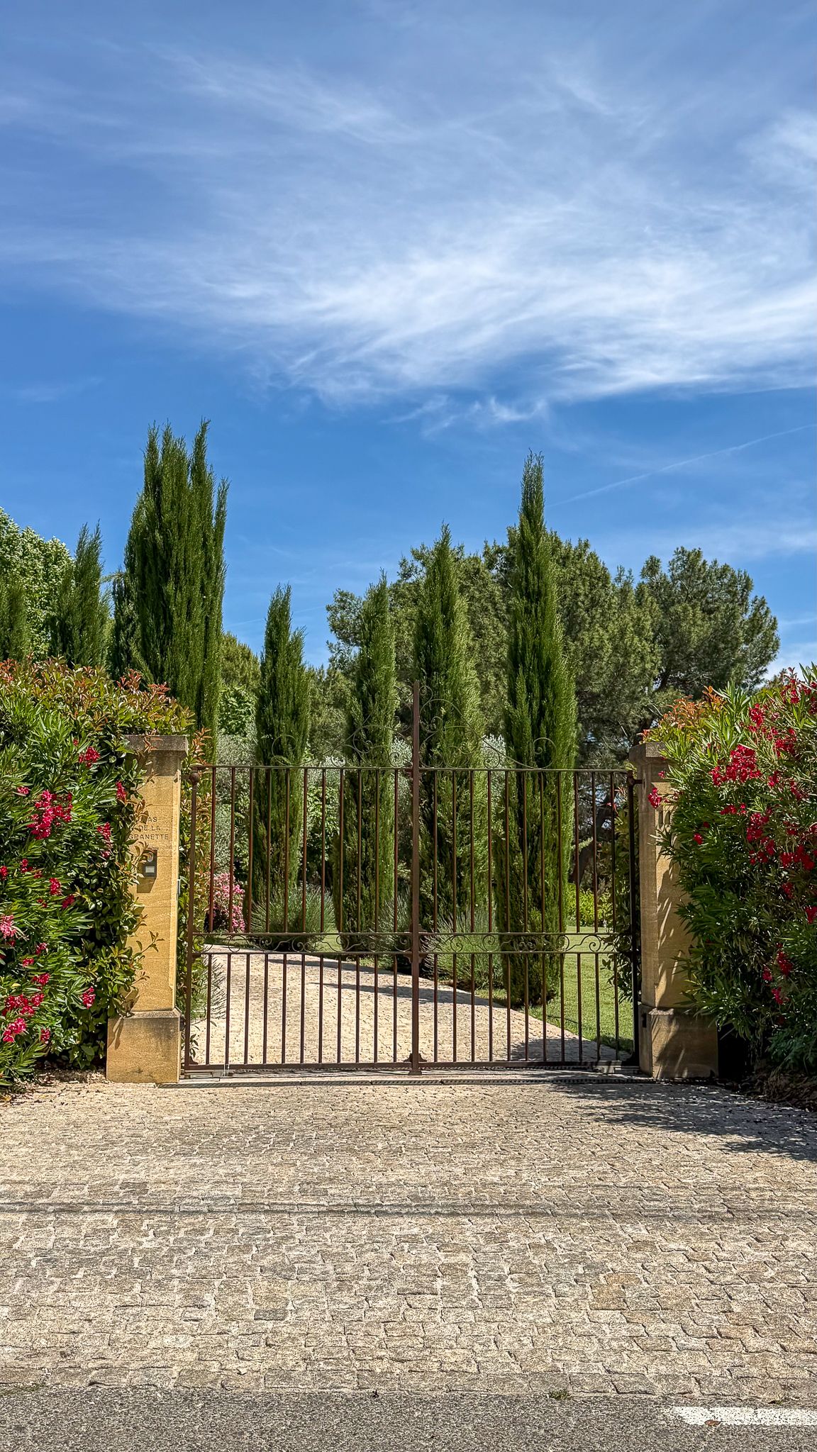 A gated entrance with a gravel driveway leading to a building.