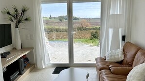 A living room with a brown leather sofa, a white coffee table, and a television on a wooden stand. - Le Pavillon blanc - CAHUZAC-SUR-VERE (CAHUZAC-SUR-VERE)