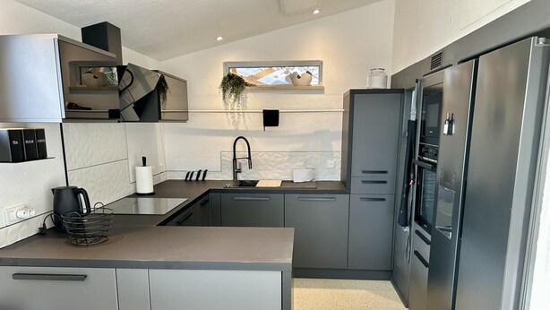 A modern kitchen with grey cabinetry, a stainless steel refrigerator, and a window with a view of mountains. - Le Pavillon blanc - CAHUZAC-SUR-VERE (CAHUZAC-SUR-VERE)