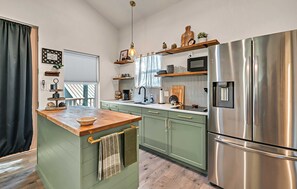 A kitchen with green cabinets, a wooden countertop, a stainless steel refrigerator, and a hanging light fixture. - Casita by the Lake | Boat Parking | Walk to Lake (Belton)