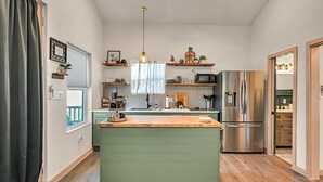 Une cuisine compacte dotée d’un îlot central, de planchers en bois et d’appareils électroménagers en acier inoxydable.