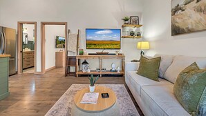 Un salon moderne avec un canapé, une table basse et un téléviseur posé sur un meuble en bois.