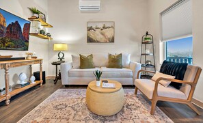A living room with a white sofa, a round coffee table, a wooden side table, a bookshelf, and a painting on the wall. - Casita by the Lake | Boat Parking | Walk to Lake (Belton)