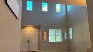Une pièce spacieuse avec un plafond haut, de grandes fenêtres et une porte.