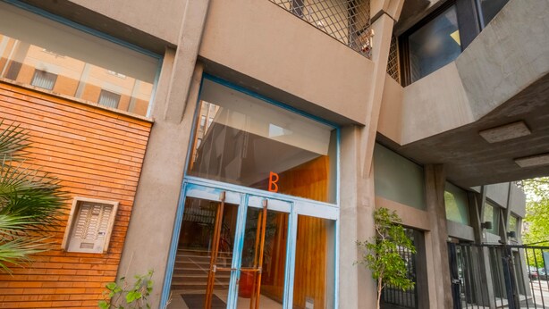 A building entrance with a blue-framed glass door, a wooden wall to the left, and a small potted plant on the right. - Trastevere 8 Guests Apartaments WIFI (Roma)