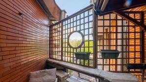A balcony with a view of a brick wall, a wooden railing, and a circular window. - Trastevere 8 Guests Apartaments WIFI (Roma)