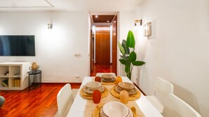 A dining area with a table set for four, a television, and a bookshelf. - Trastevere 8 Guests Apartaments WIFI (Roma)