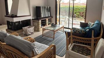 Una sala de estar con muebles de mimbre, un televisor y una chimenea.