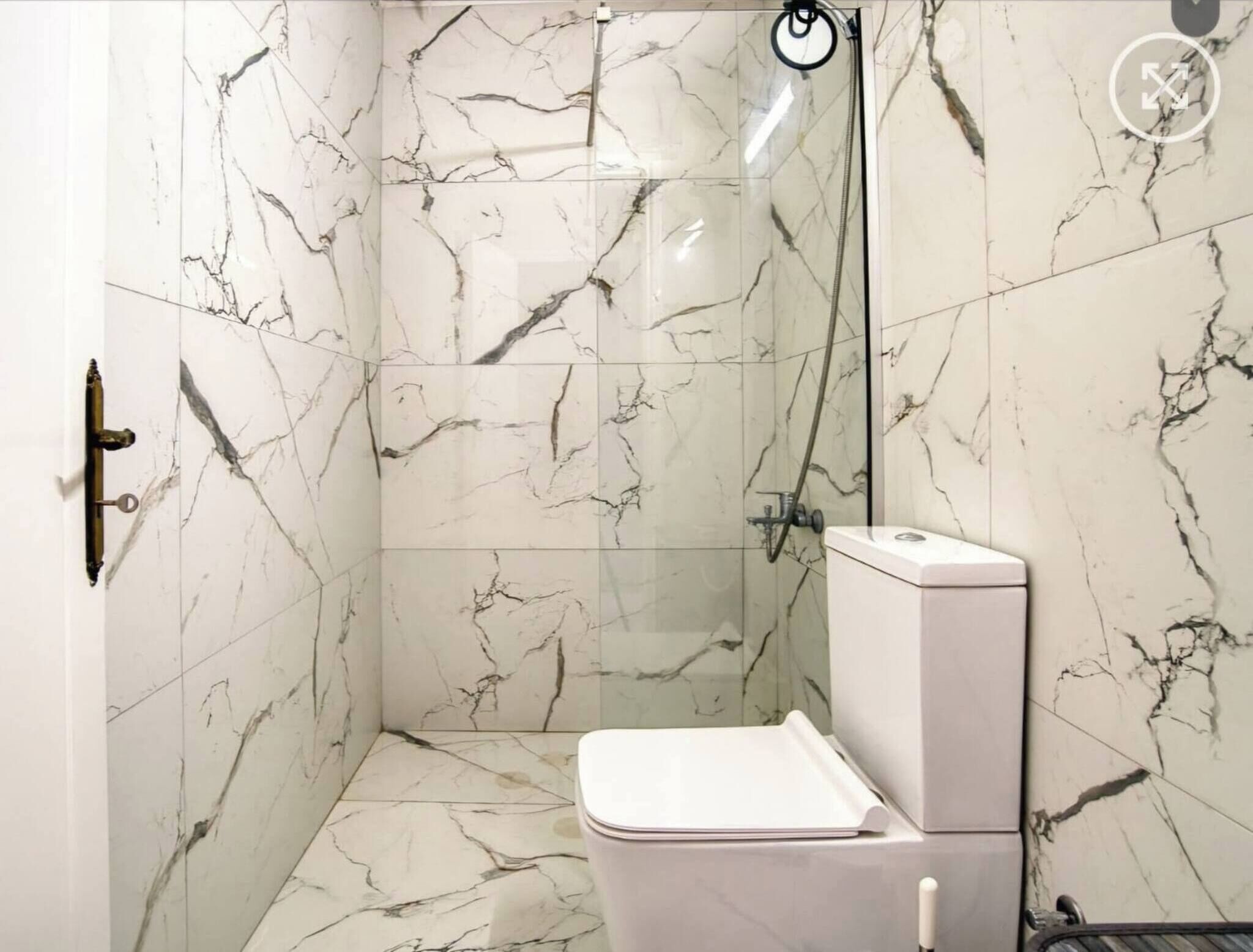 Un baño con ducha, inodoro y paredes de mármol.
