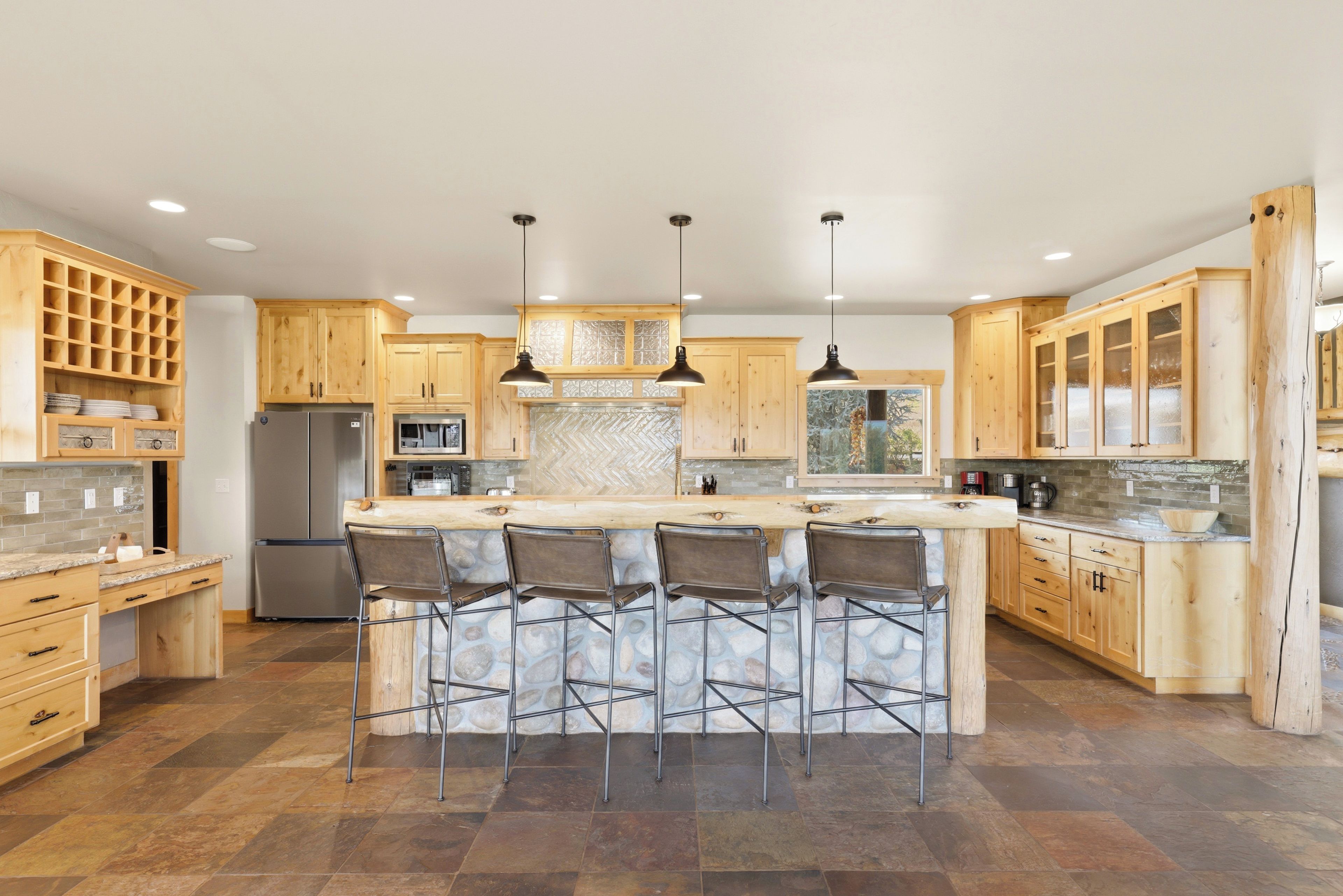 A modern kitchen with a central island, bar stools, and wooden cabinetry.
