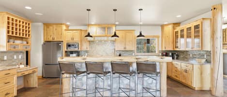 A modern kitchen with a central island, bar stools, and wooden cabinetry.