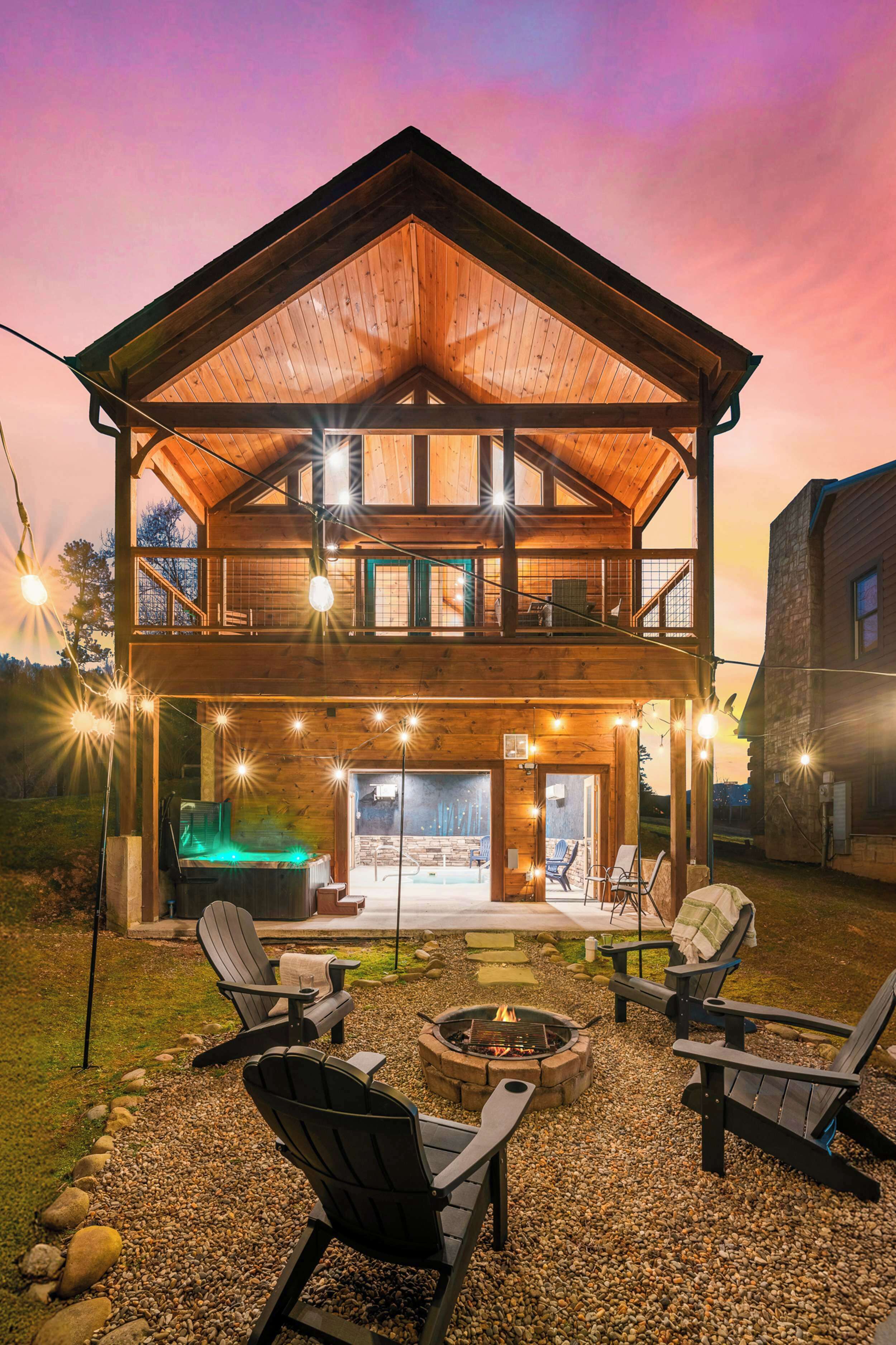 Une cabane en bois à deux étages, dotée d’un balcon, d’un espace extérieur aménagé pour s’asseoir et d’un foyer.
