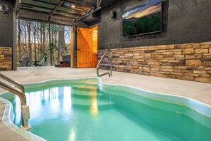 A swimming pool with a stone wall and a wooden door leading outside. - Saltwater Pool • Hot Tub • Firepit (Gatlinburg)