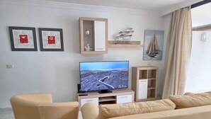 A living room with a TV, two framed artworks, a wooden cabinet, and a sailboat painting. - Naos Costa Atlantica - Puerto Naos (Puerto Naos)