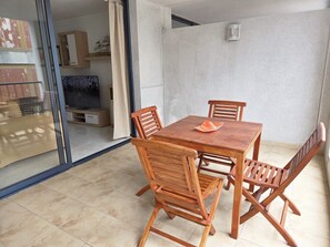 A dining area with a wooden table and chairs, a glass door leading to another room, and a tiled floor. - Naos Costa Atlantica - Puerto Naos (Puerto Naos)