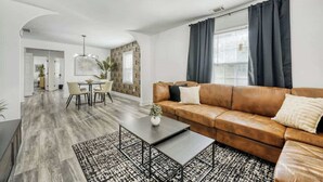Ein modernes Wohnzimmer mit Ledersofa, Couchtisch und Essbereich mit Tisch und Stühlen.