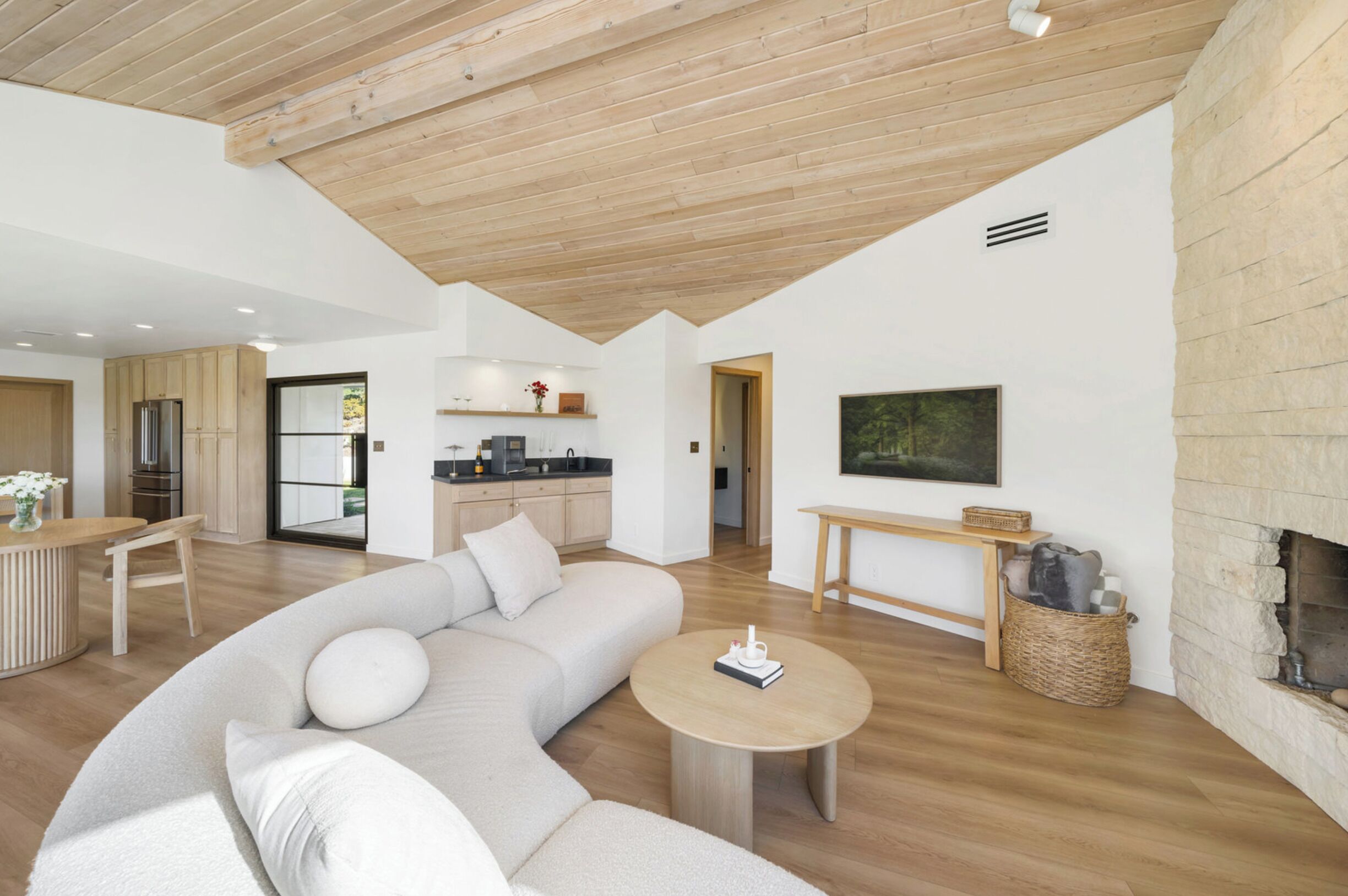 Ein modernes Wohnzimmer mit Holzboden, einer großen Couch, einem Couchtisch und einem Kamin.