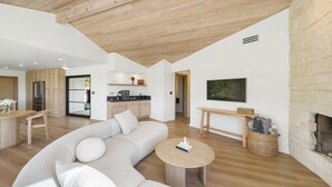 Ein modernes Wohnzimmer mit Holzboden, einer großen Couch, einem Couchtisch und einem Kamin.