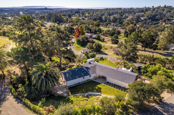 A residential property with a large house, a well-maintained lawn, and surrounding trees. - Peaceful Wine Country Retreat - Valley & Ocean Views - Outdoor Fireplace & BBQ! (Arroyo Grande)