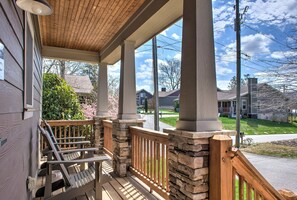 A porch with wooden chairs, stone pillars, and a view of a residential street. - Home Near Biltmore Estate | Pet-Friendly 3BR (30-Night Minimum + Year-Long Lease Option) (Asheville)