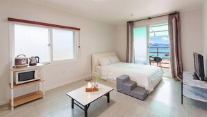 Hotelkamer met een bed, een kleine tafel met een mand en glazen, een magnetron, een televisie en een balkon met uitzicht.