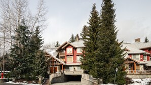 Eine mehrstöckige Lodge mit zentralem Eingang, umgeben von hoch aufragenden immergrünen Bäumen.