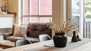 Ein Esstisch mit einer Blumenvase, einer Kerze und einem Fenster mit Jalousien im Hintergrund.
