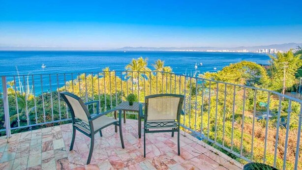 A balcony with two chairs and a table overlooking a coastal view. - Department Pino Amapas (Puerto Vallarta)