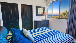 A bedroom with a large bed, two doors, a dresser, and a window with a view of the sea. - Department Pino Amapas (Puerto Vallarta)