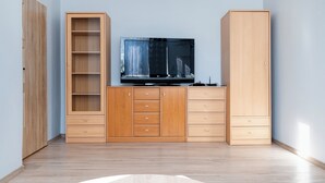 A room with a wooden cabinet, a TV, and a wardrobe. - Park nad Jasieniem Studio (Łódź)