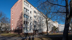 A multi-story building with a mix of brick and plaster facades, large windows, and a visible fire hydrant. - Park nad Jasieniem Studio (Łódź)
