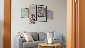 A modern living room with a grey sofa, a round wooden coffee table, and three framed artworks on the wall. - Mokotów Urban Cozy Apartment (Warszawa)
