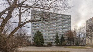 A multi-story residential building with a flat facade, surrounded by trees and a paved area. - Mokotów Urban Cozy Apartment (Warszawa)