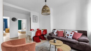Ein modernes Wohnzimmer mit einer braunen Couch, roten Sesseln, einem runden Couchtisch und einer Pendelleuchte.