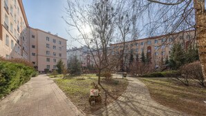 Ein gepflasterter Weg führt zu einem Gebäude mit mehreren Fenstern und Balkonen.