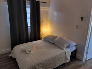 A bedroom with a bed, curtains, a nightstand, and a lamp. - Little Havana Urban Escape  14 (Miami)