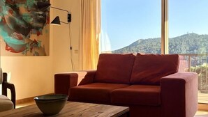 Ein rotes Sofa, ein Holztisch und ein Gemälde an der Wand.