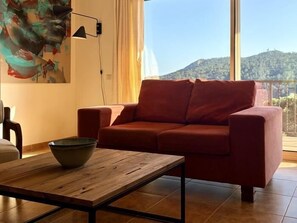 A red sofa, a wooden coffee table, and a painting on the wall. - Calma Mar by Costabravaway (Sant Feliu de Guíxols)