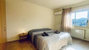 Ein Schlafzimmer mit einem Bett, einem Nachttisch, einem Fenster mit Vorhängen und einer Heizung.