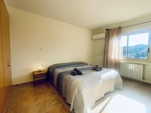 A bedroom with a bed, a nightstand, a window with curtains, and a radiator. - Calma Mar by Costabravaway (Sant Feliu de Guíxols)