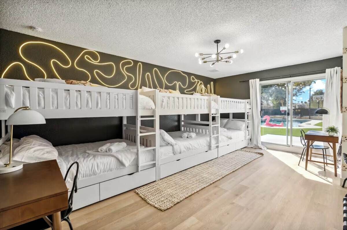Ein modernes Schlafzimmer mit Stockbetten, einem Schreibtisch und Blick auf einen Swimmingpool.