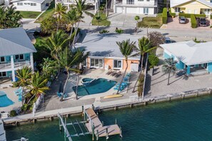 An aerial view of a resort with a swimming pool, palm trees, and a dock. - Casa de Rosa - Key Colony Beach Waterfront Pool Home (Key Colony Beach)