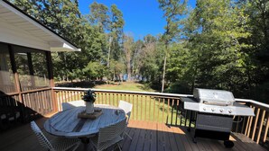 A deck with a grill, a round table with chairs, and a view of trees. - Family-Friendly 5BR Lake Hartwell Lakefront Getaway with Dock ~ Sunset Shores (Martin)