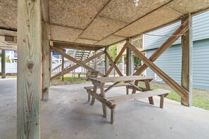 A wooden picnic table under a covered area with a concrete floor. - "Pirate Pride" a Charming 3 Bedroom, 2 Bathroom, Dunes Home! (Holden Beach)