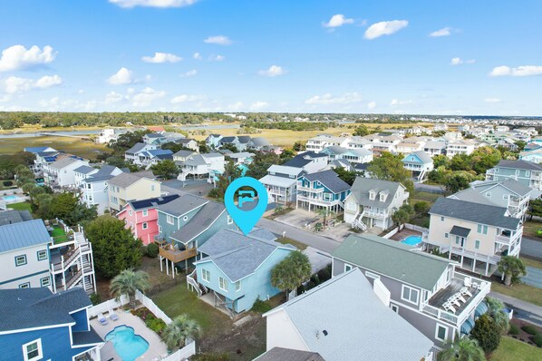 A residential area with houses, a swimming pool, and a body of water in the background. - "Pirate Pride" a Charming 3 Bedroom, 2 Bathroom, Dunes Home! (Holden Beach)